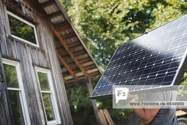 Ein Mann mit einem Solarpanel auf einer grünen Baustelle  der an einem grünen Bauprojekt arbeitet.