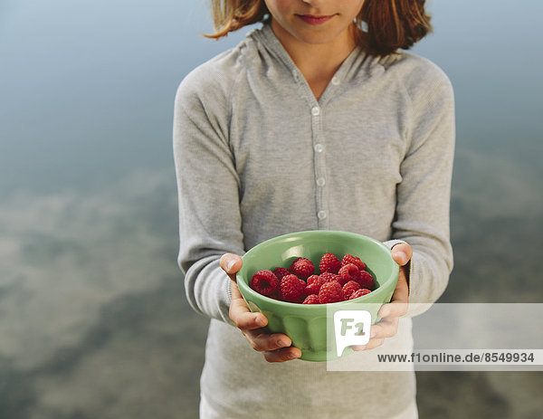 Neunjähriges Mädchen hält Schale mit Bio-Himbeeren