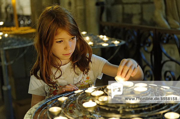 Girl lighting a devotional candle at Notre-Dame de Paris or Notre-Dame Cathedral  Ile de la Cité  4th Arrondissement  Paris  France