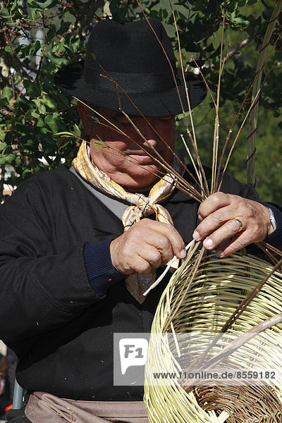 Älterer Mann in Tracht  beim Flechten eines Korbes auf einem traditionellen Handwerksmarkt  Ibiza  Spanien