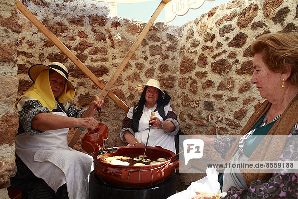 'Ältere Frauen in traditioneller Tracht beim Backen von ''Bunyols''  typische frittierte Teigringe  auf einem traditionellen Handwerksmarkt  Ibiza  Spanien'