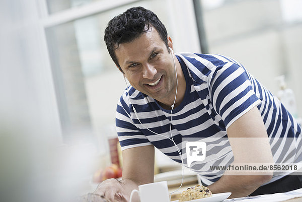 An office or apartment interior in New York City. A man in a striped tee shirt leaning on the breakfast bar.