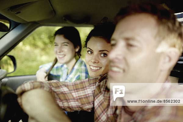 Drei Passagiere in der Kabine eines Pickup-Trucks. Ein junger Mann am Steuer. Zwei junge Frauen sitzen neben ihm.