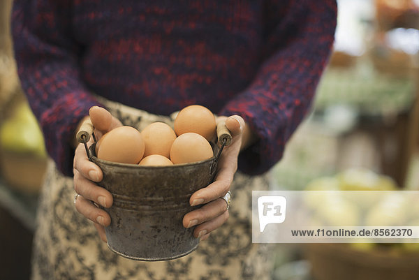 Organic Farmer at Work. A woman carrying a container of eggs.