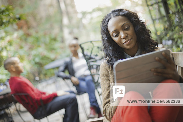 Scenes from urban life in New York City. Outdoors. Two people in background. A woman using a computer tablet or pad.