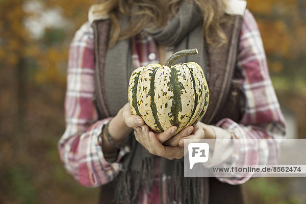 Organic farm. A woman holding a large striped squash vegetable.
