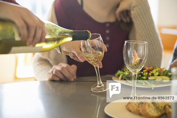 Ein junger Mann und eine junge Frau sitzen zusammen bei einer Mahlzeit und trinken Wein.