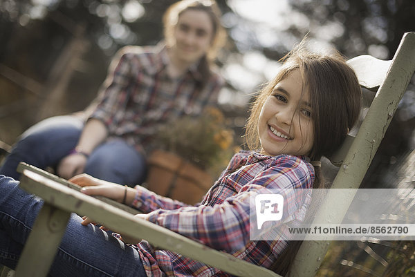 Zwei Kinder sitzen im Freien in einem Garten auf einem Biobauernhof.