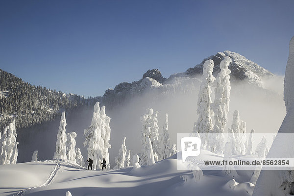 Two hikers enjoy a blue bird day in the middle of winter in the snow covered Cascade Mountains.