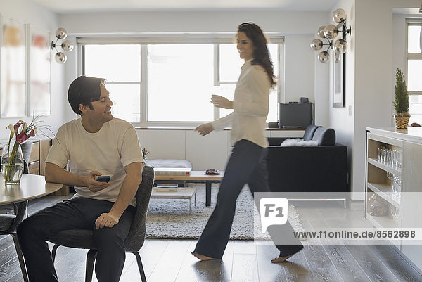 Couple at Home  Man using smartphone  Woman walking past
