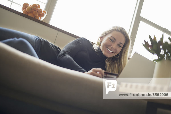 Woman at home  on-line shopping on sofa