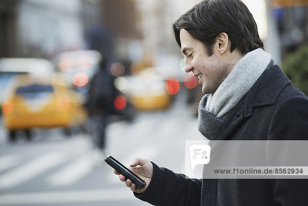 Mann auf belebter Straße mit Smartphone