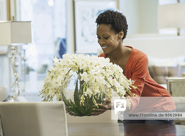 Frau stellt Blumenvase auf den Tisch