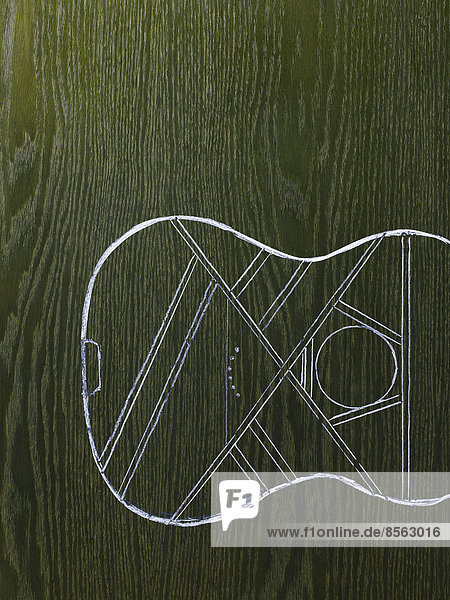 Ein Linienzeichnungsbild auf einem Hintergrund mit natürlicher Holzmaserung. Resonanzboden und Korpus eines Musikinstruments  einer Gitarre.