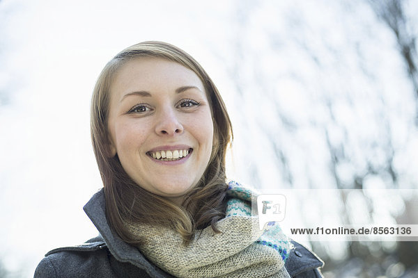 A young woman in a scarf and coat  outside on a winter day.