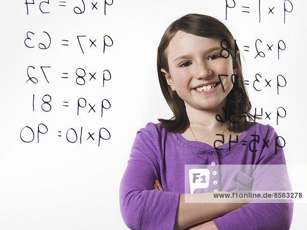 Ein Kind schaut auf eine Reihe von Multiplikationstafeln  die auf eine durchsichtige Fläche geschrieben sind.