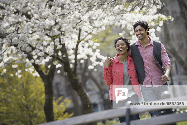 People outdoors in the city in spring time. New York City park. A man and woman side by side.