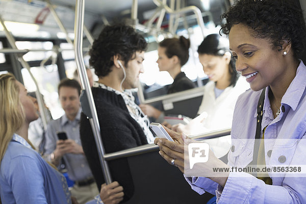New York City park. People  men and women on a city bus. Public transport. Keeping in touch. A young woman checking or using her cell phone.
