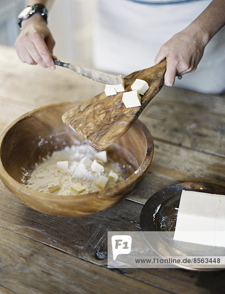 A domestic kitchen. A woman preparing a meal  mixing flour and fat to create pastry.