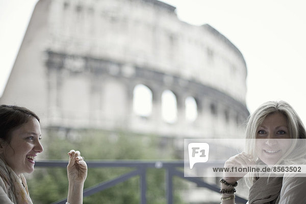 Zwei Frauen saßen auf einer Terrasse mit Blick auf das riesige römische Amphitheatergebäude  das Kolosseum in Rom.