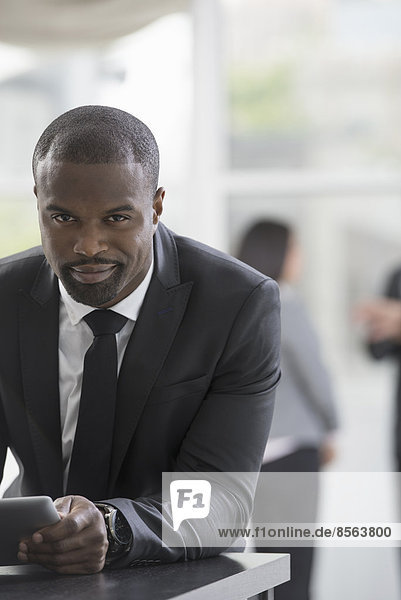 Young professionals at work. A man in a business suit  using a digital tablet.