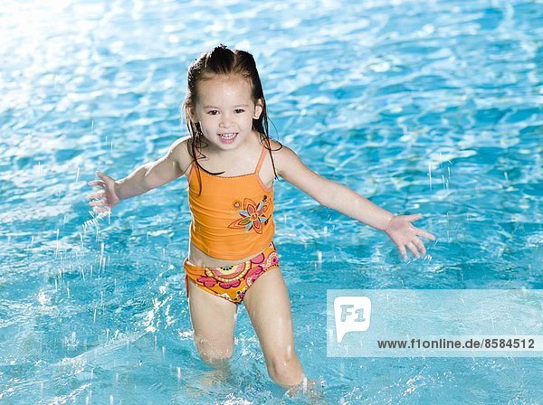 Little girl playing with water at the swimming pool
