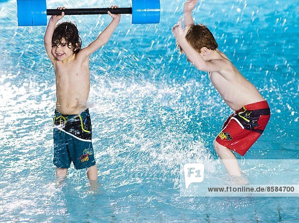 Two boys splashing at the swimming pool