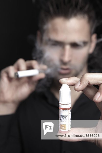 Frankreich  junger Mann  der eine elektronische Zigarette raucht.