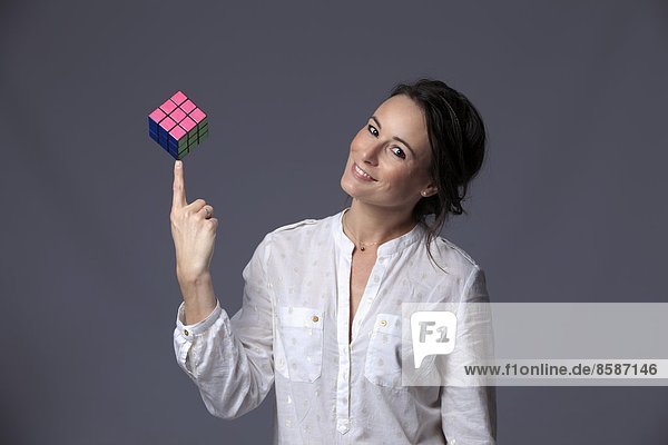 France  young woman in studio holding Rubik' S cubes in balance on her finger.