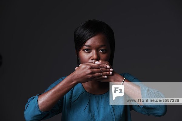 France  young woman on grey background  hands on her mouth.