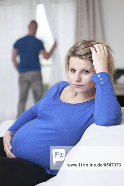 Frankreich,  traurige schwangere Frau,  ihr Mann im Hintergrund.