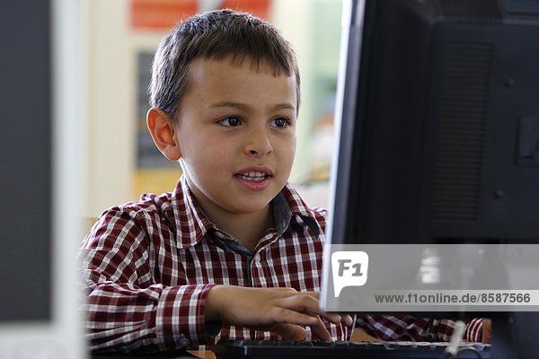 7-year-old boy using a computer. France.