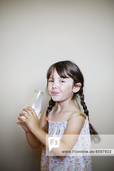 Ein kleines Mädchen mit einer Flasche Milch.