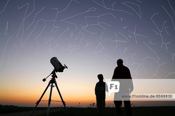 Seine et Marne. Man trying to show his 5 year old son constellations and their layout. Planetarium effect. Telescope.