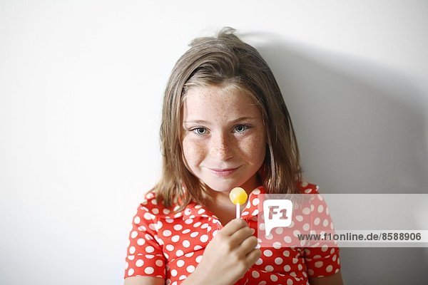 ein kleines Mädchen  das einen Lolli isst.