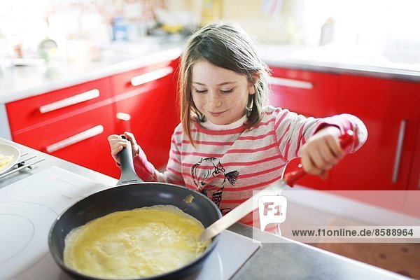 A little girl making crepes
