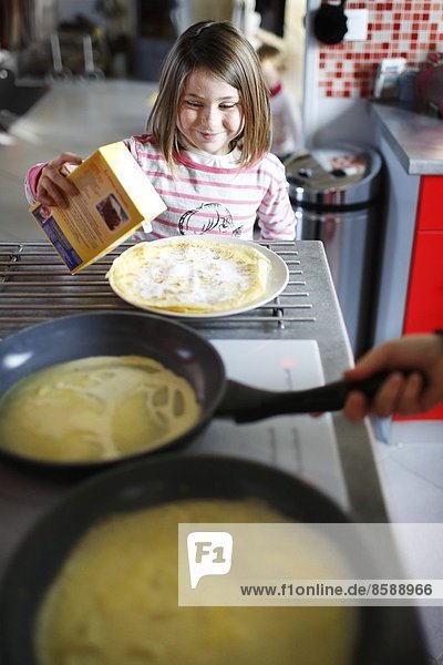 Ein kleines Mädchen macht Crêpes.
