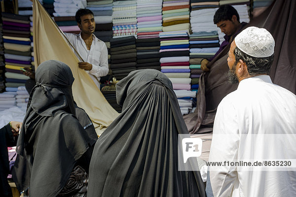 Two Muslim women and a man buying material at Mangaldas Market  Mumbai  Maharashtra  India