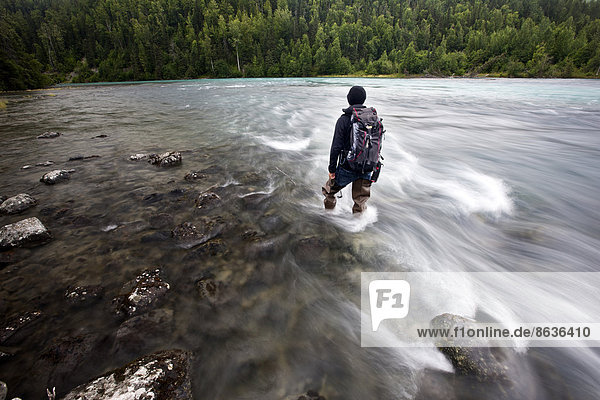 Man wearing fishing boots on the bank of Lowe River near Valdez  Alaska  USA