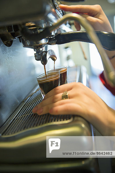 A young woman making coffee using a large coffee machine.