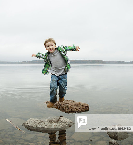 Ein Tagesausflug am Ashokan-See. Ein Junge springt über Trittsteine.