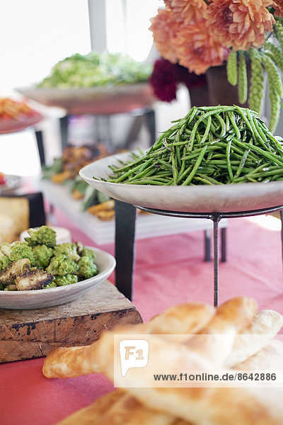 Biologisch zubereitete Salate  Gemüse und Obst auf Gerichten  die für eine Party ausgelegt sind. Ein gedeckter Tisch. Blumen in einer Vase. Ein Imbissstand auf einem Bauernhof.