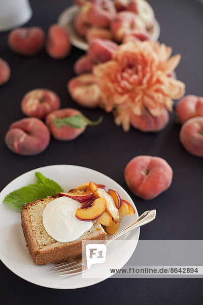 Fresh fruit and flowers. A slice of organic peach cake with a serving of creme fraiche and doughnut peaches.