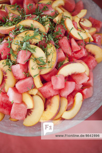 Biologisch zubereitetes Bauernhof-Partyessen. Sommerlicher Obstsalat mit Wassermelone,  Pfirsichen und Minze.