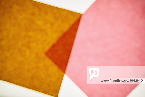 Zwei Stücke Recycling-Baupapier  braun und rosa mit einem kleinen überlappenden Dreieck.