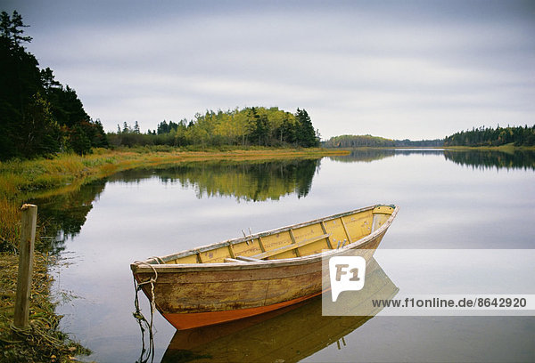 Ein kleines hölzernes Dory oder Ruderboot  vertäut auf flachem  ruhigem Wasser  im Hafen von Savage auf Prince Edward Island in Kanada.