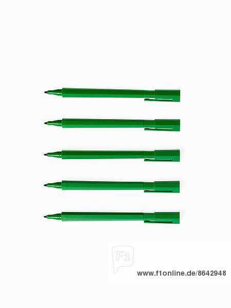 Büromaterial. Grün gefärbte Stifte  Filzfedern und Federmäppchen  in einer Reihe angeordnet.