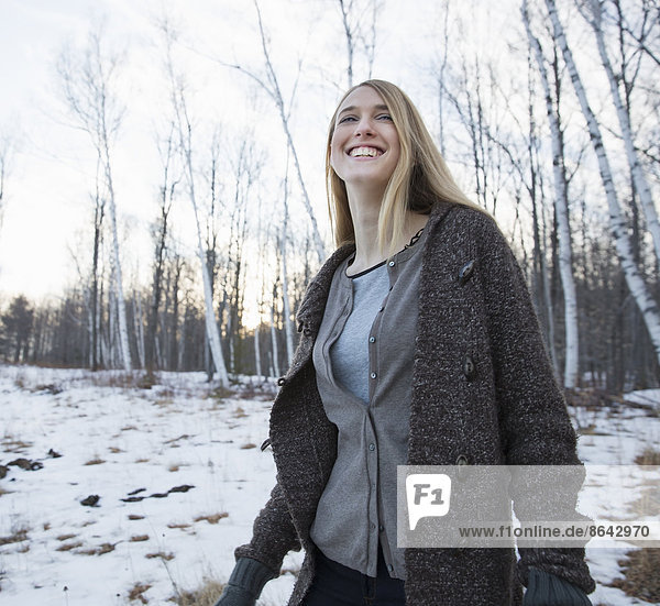 Eine junge Frau mit langen blonden Haaren an einem Wintertag im Freien.