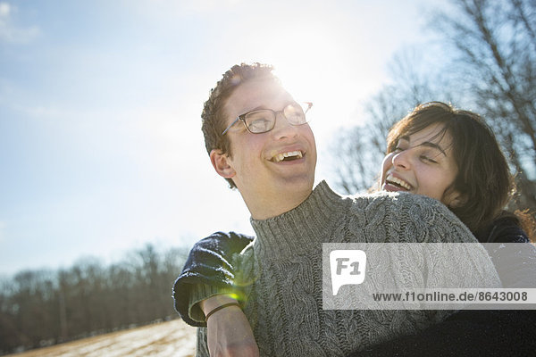 Zwei Menschen  ein Mann und eine Frau  die sich umarmen und lachen. Ein Spaziergang an einem Wintertag.