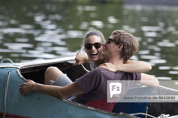 Young couple riding paddle boat  laughing